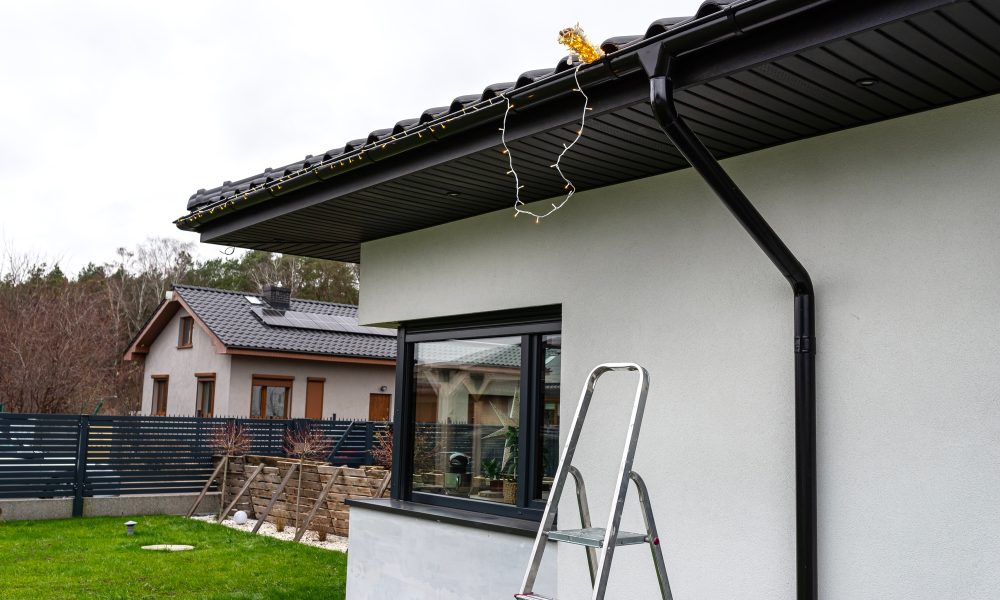 Installing LED lights along the gutter around the house, decorating the house for the holidays.