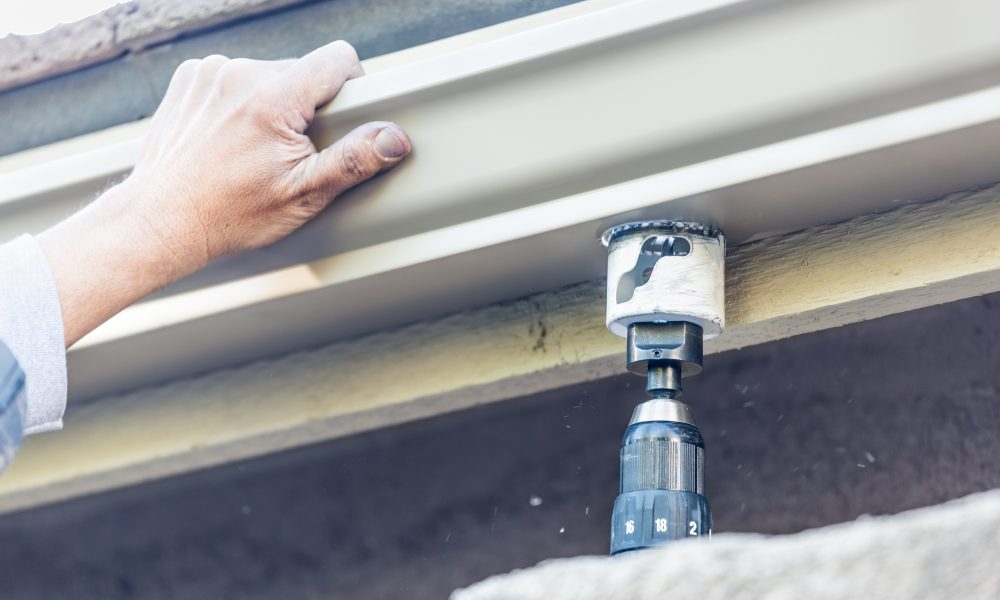 Worker Attaching Aluminum Rain Gutter to Fascia of House